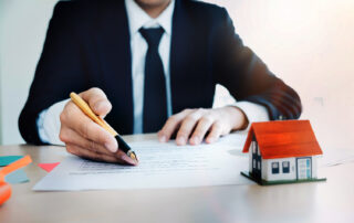 Person in suit inspecting paperwork for loan underwriting process. There is a small house model in front of them.